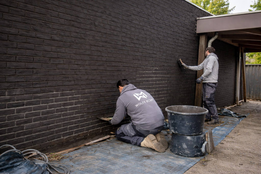 Vakman repareert voegen aan buitenmuur met mortel — Wolfe Bouw Breda